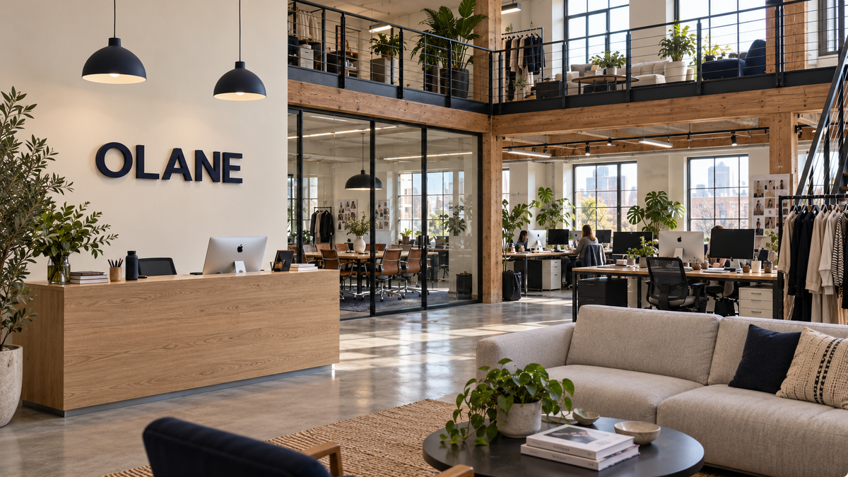 OLANE office reception with the official wall logo and an open-plan fashion workspace
